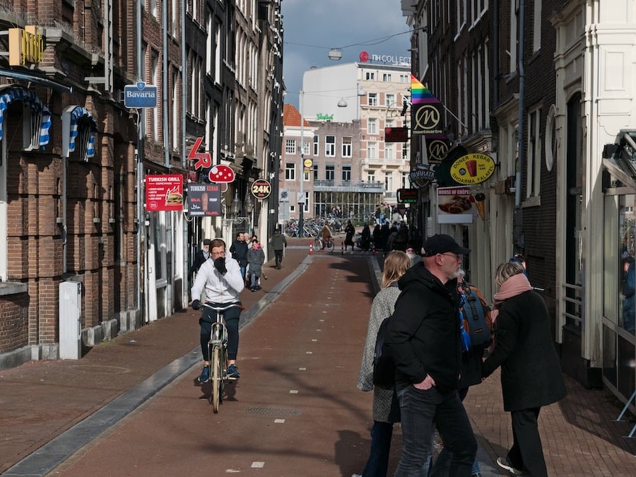Livlig stadsgata med cyklister och fotgängare.