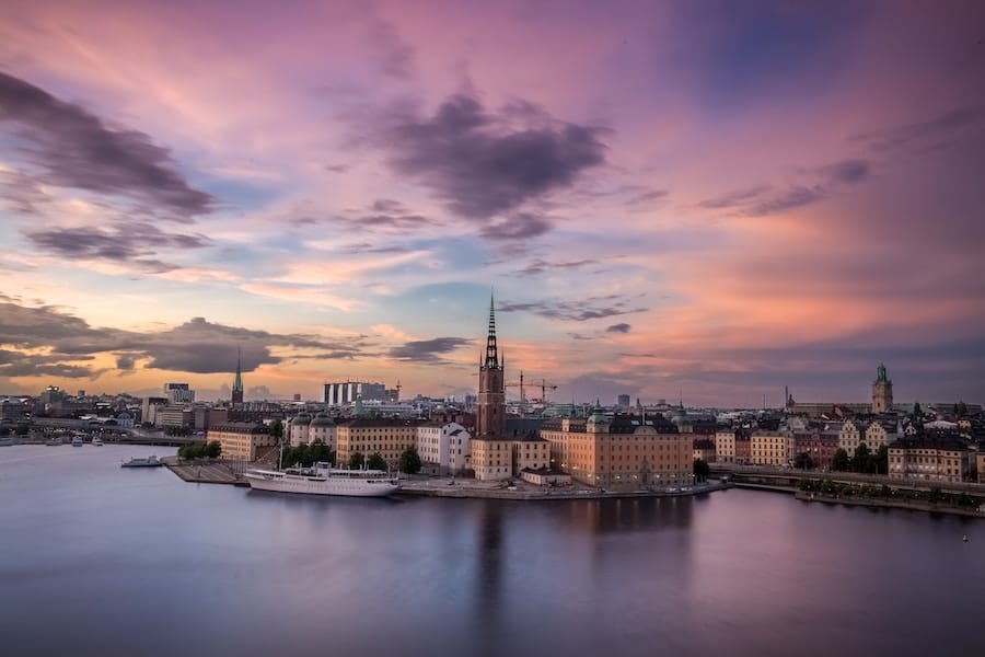Stockholms siluett vid solnedgång över vatten.