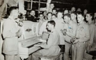 Soldater sjunger vid piano, historiskt foto.