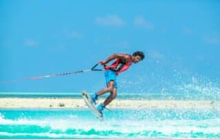 Person utför wakeboardtrick på turkost vatten.