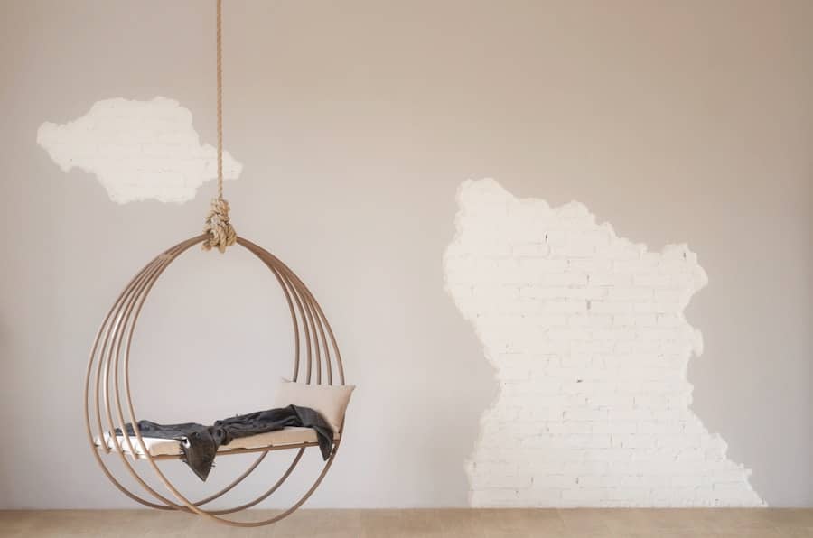 Rund hängstol med kudde i minimalistiskt rum.