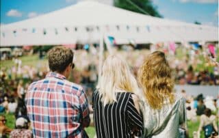 Tre personer ser på festival utomhus.