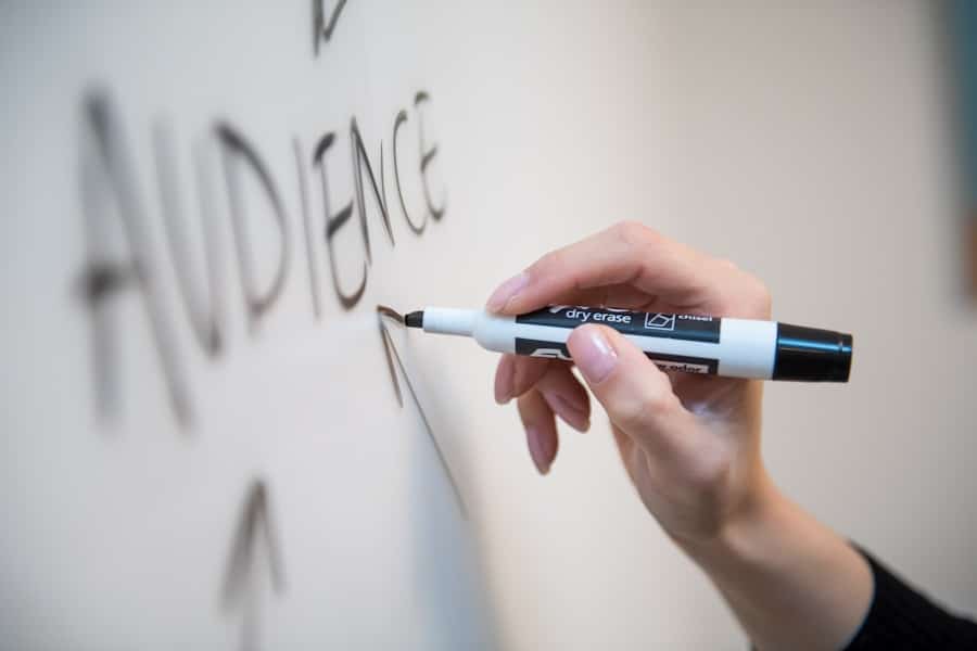 Hand skriver "AUDIENCE" på whiteboard med tusch.
